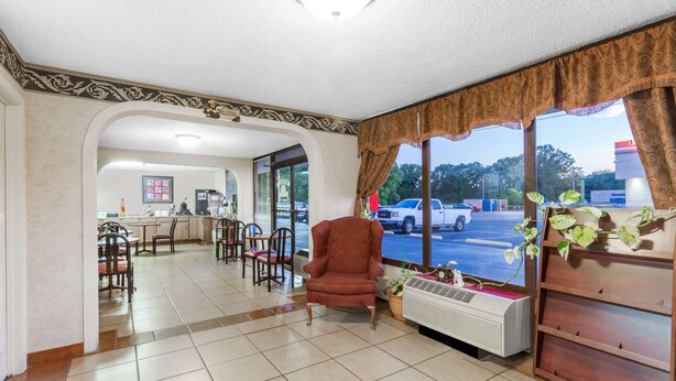 A hotel lobby with a red armchair, a coffee machine, and a view of the parking lot. - Days Inn by Wyndham Martin (Martin)
