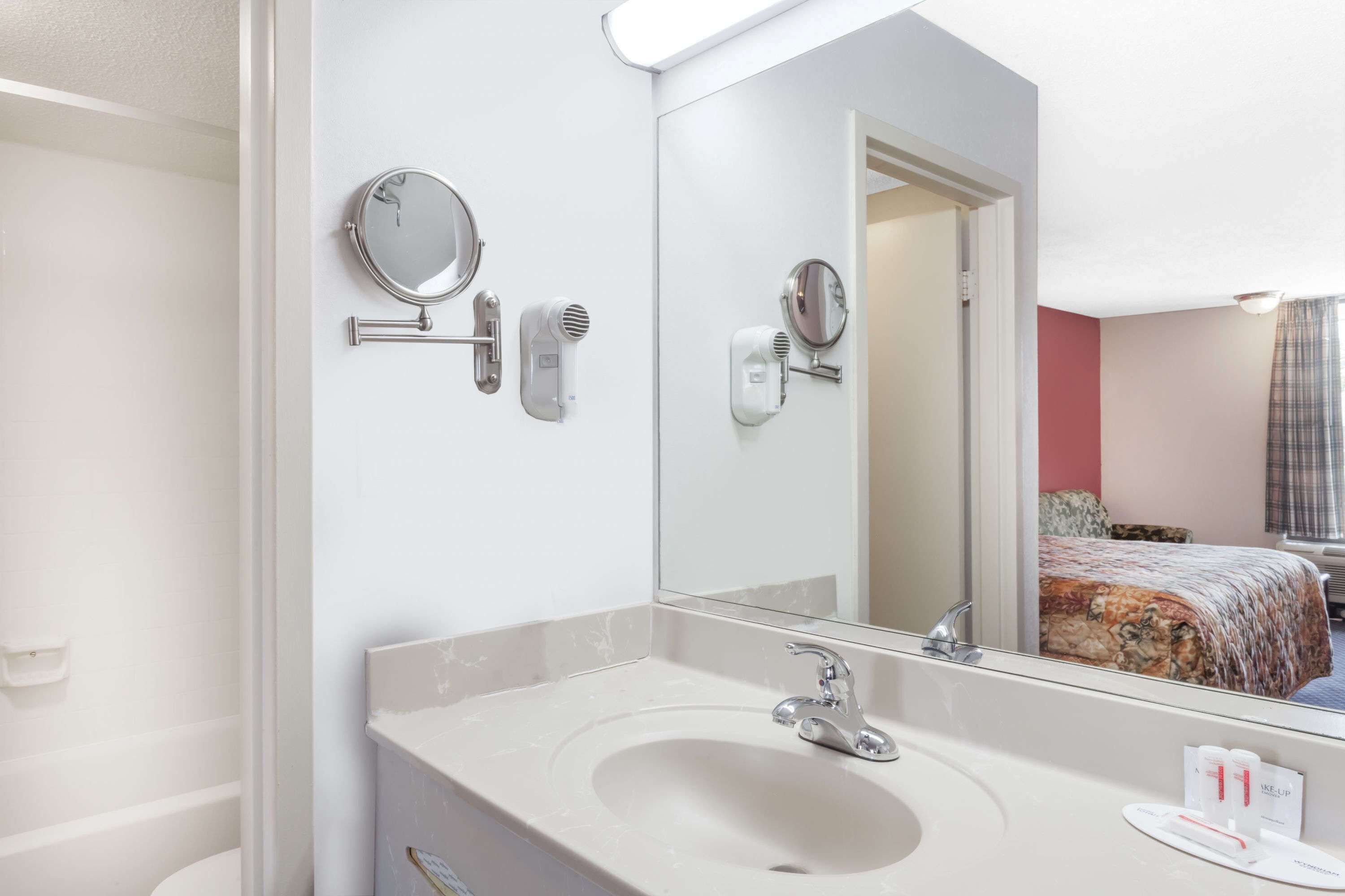 A hotel bathroom with a large mirror, a sink, and a towel rack.