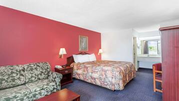 Et hotelværelse med seng, sofa, skrivebord og stol.