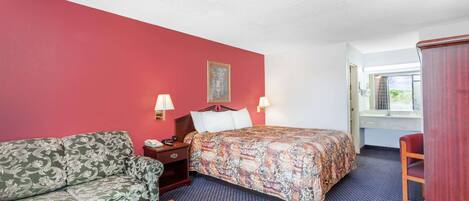 A hotel room with a bed, a sofa, a desk, and a chair.
