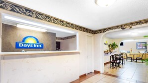 A Days Inn reception area with a marble counter, a 'Welcome' sign, and a view of the dining area with chairs and a table. - Days Inn by Wyndham Martin (Martin)