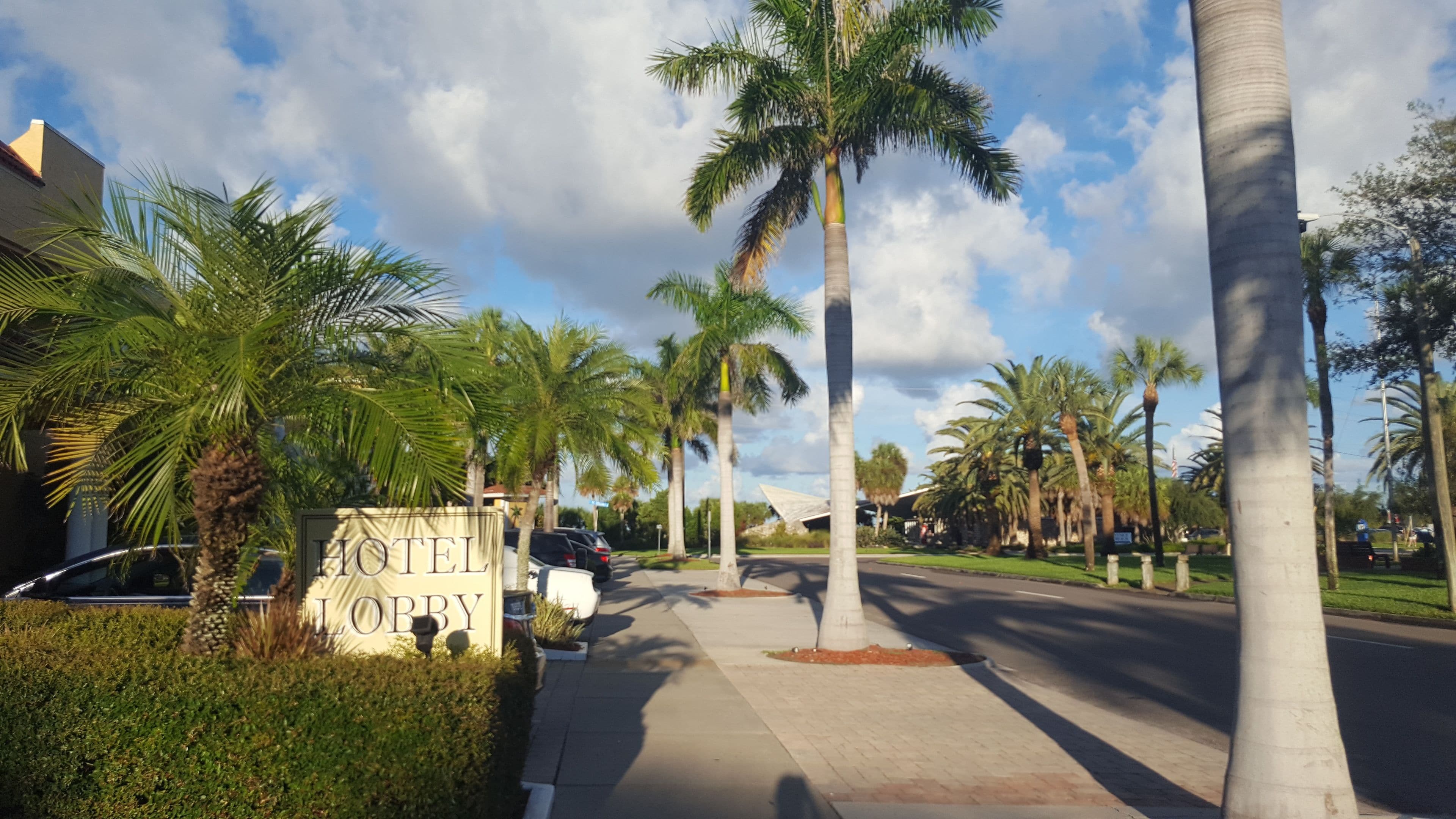 A hotel lobby with palm trees, a car, and a sign that reads "HOTEL LOBBY".