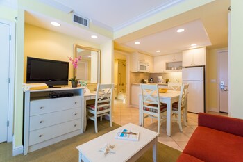 A hotel room with a bed, a desk with a chair, a television, and a mirror. at Inn at the Beach