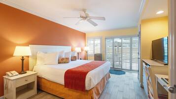 A hotel room with a bed, bedside lamps, a telephone, a ceiling fan, and a television.