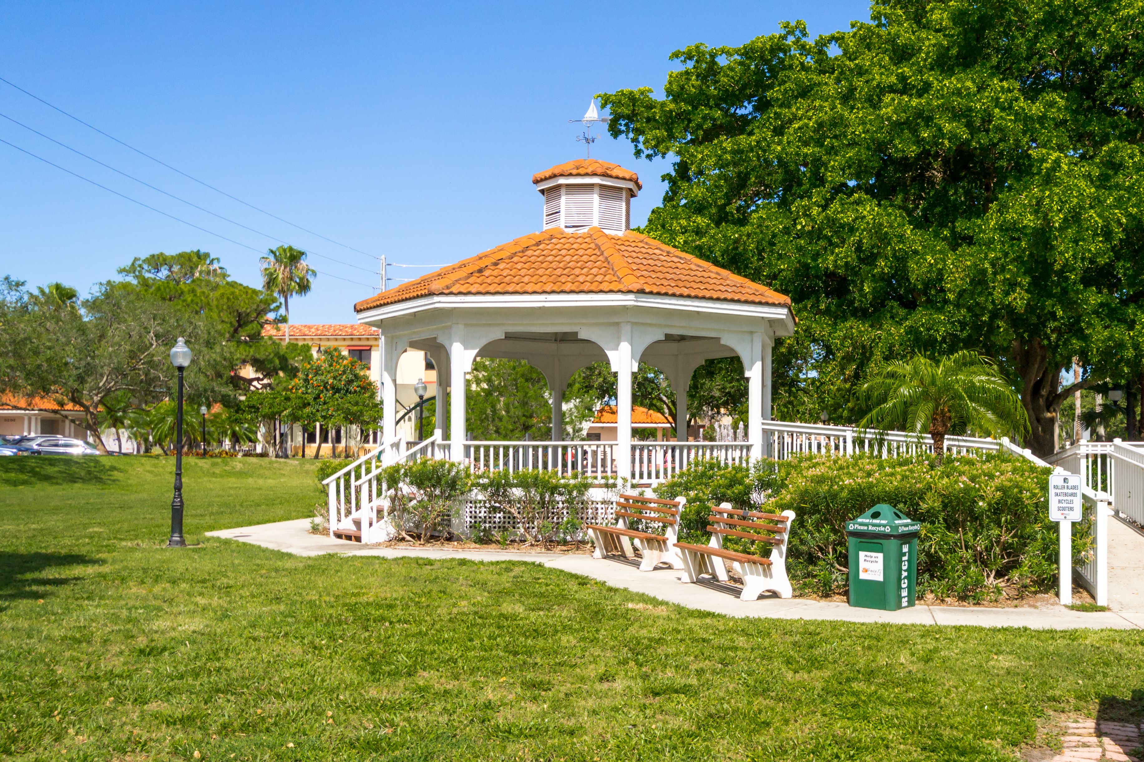 A gazebo with a tiled roof, surrounded by a white fence and benches.
