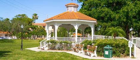 A gazebo with a tiled roof, surrounded by a white fence and benches.