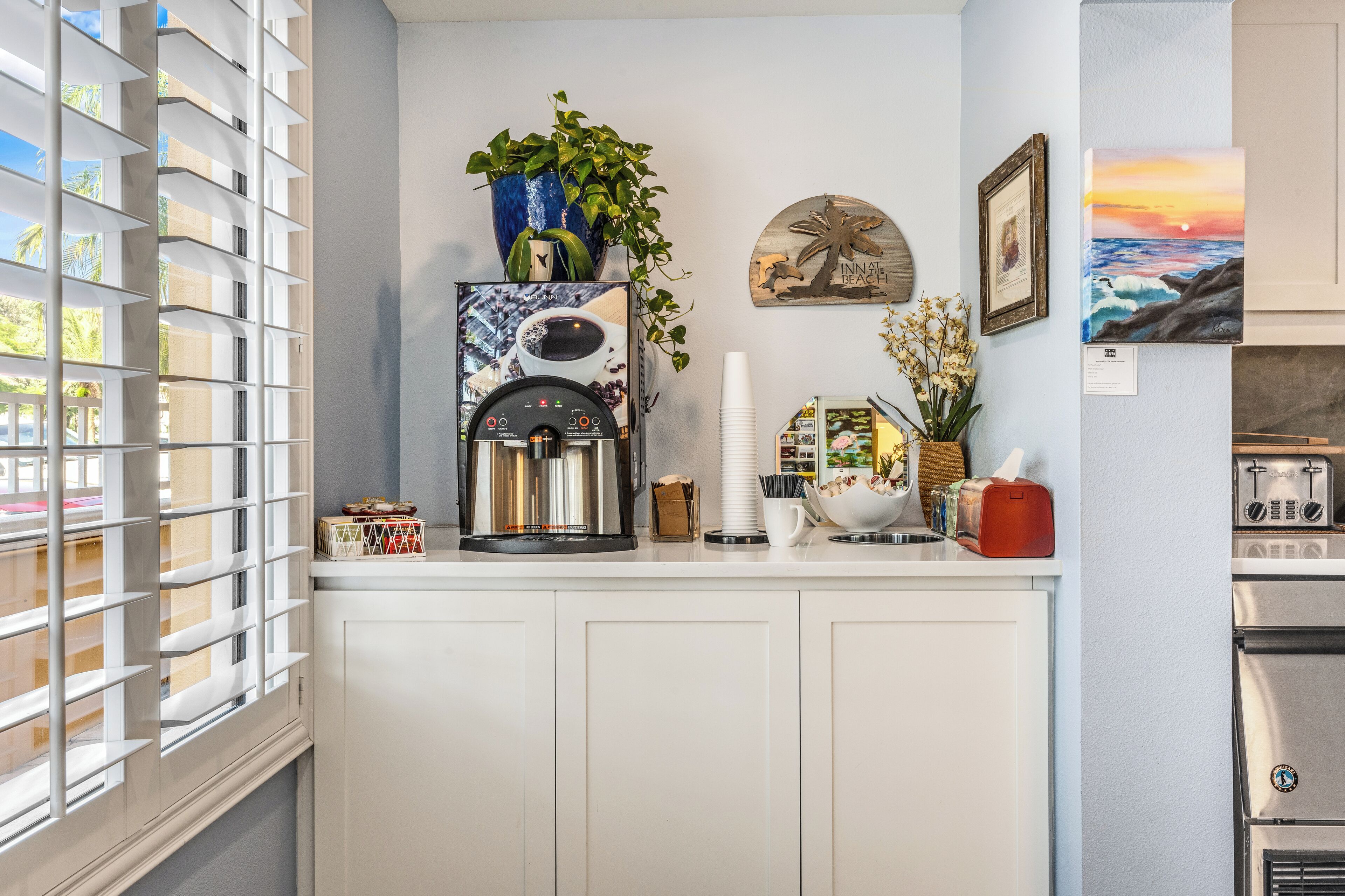 A modern kitchen with a coffee maker, a toaster, and a decorative plant.
