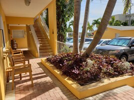 A yellow building with a staircase, outdoor seating, and a landscaped garden area.