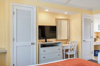 A living room with a sofa, armchairs, a coffee table, a TV, and a ceiling fan. at Inn at the Beach
