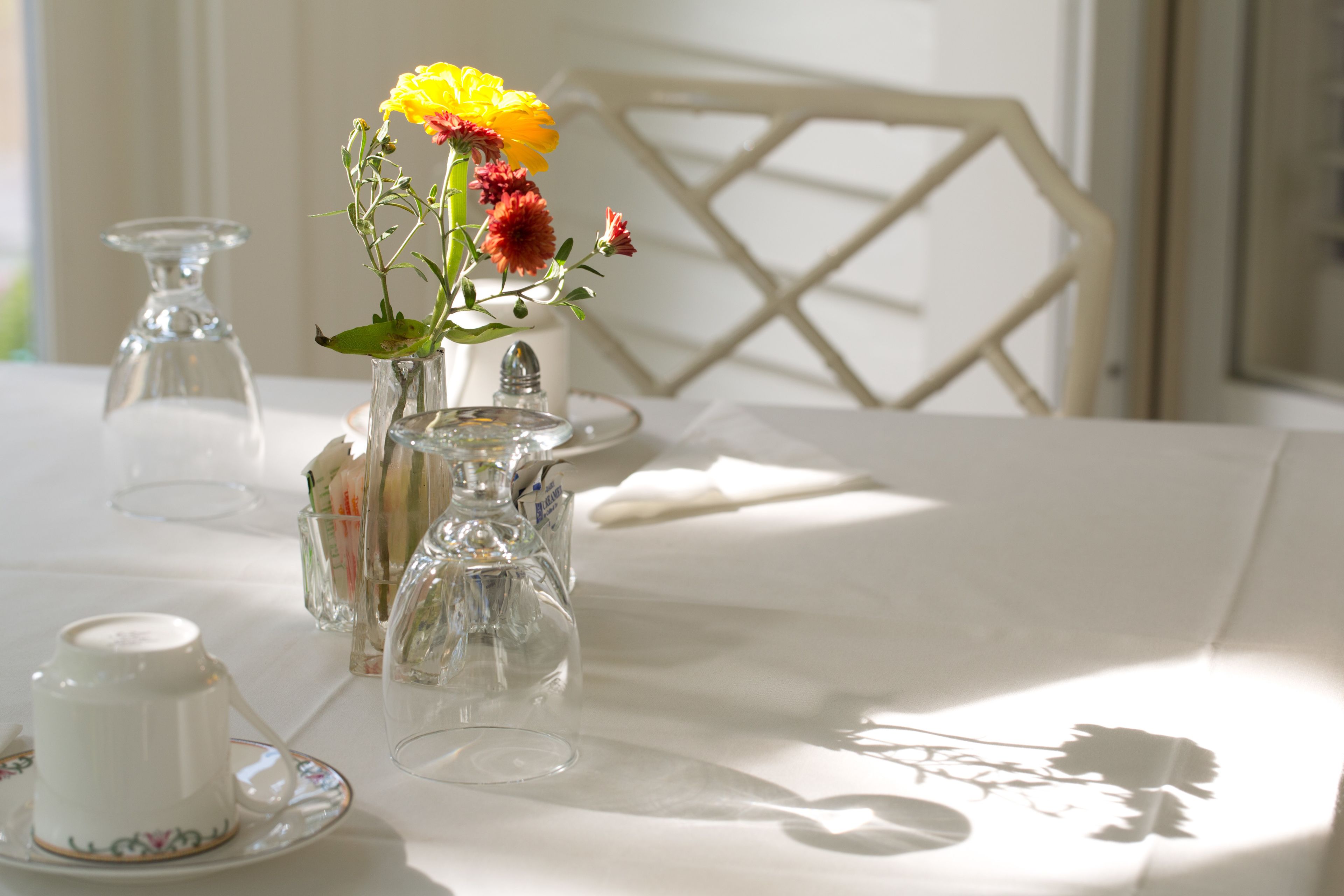 Una mesa dispuesta con cristalería transparente, una tetera blanca y un arreglo floral.