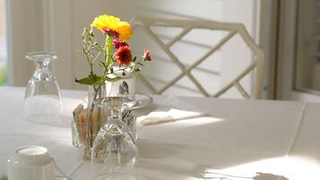 Una mesa dispuesta con cristalería transparente, una tetera blanca y un arreglo floral.