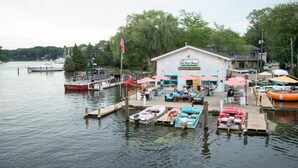 A waterfront restaurant with outdoor seating, docked boats, and a flag. - Maplewood Hotel (Saugatuck)