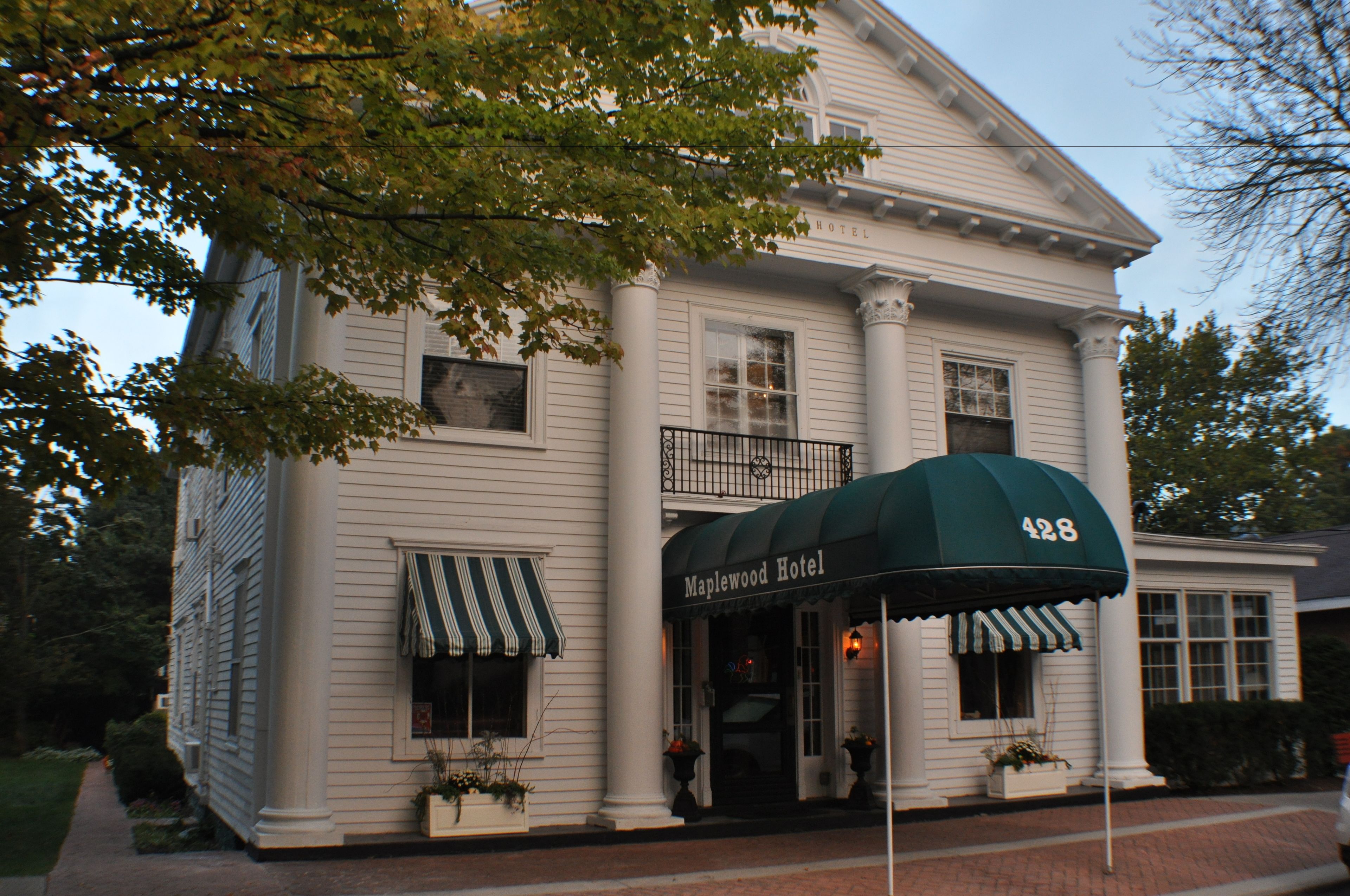 Un edificio a due piani con una tenda verde con la scritta "Maplewood Hotel".