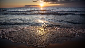 A beach with waves and a sunset. - Maplewood Hotel (Saugatuck)