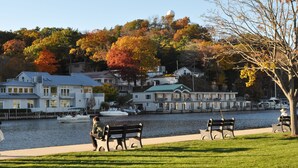 A waterfront property with a dock, boats, and a grassy area with benches. - Maplewood Hotel (Saugatuck)