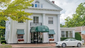 A white two-story hotel with a green awning and striped awnings on the ground floor. - Maplewood Hotel (Saugatuck)