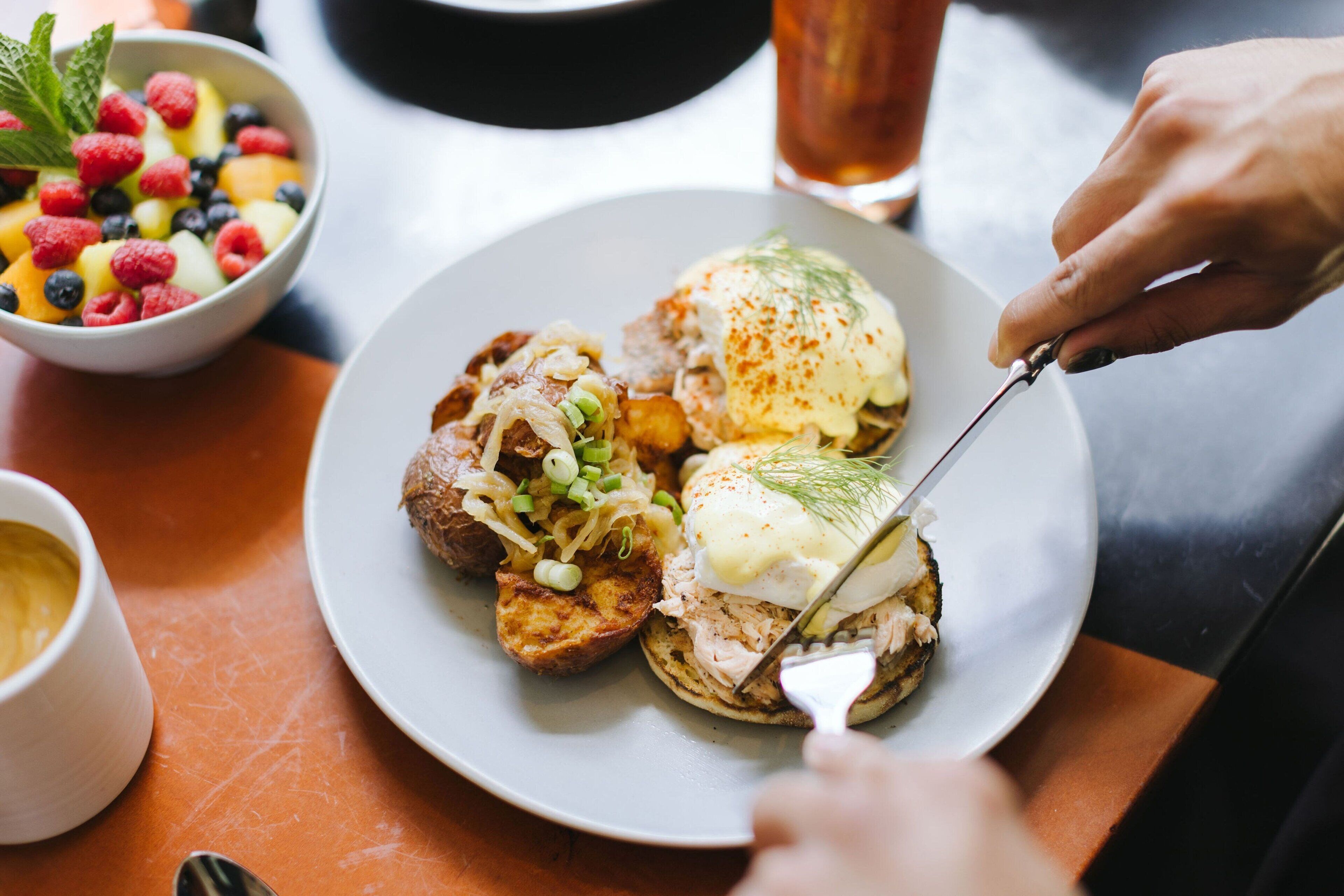 A plate with food, a bowl of fruit, and a glass of beverage on a table.
