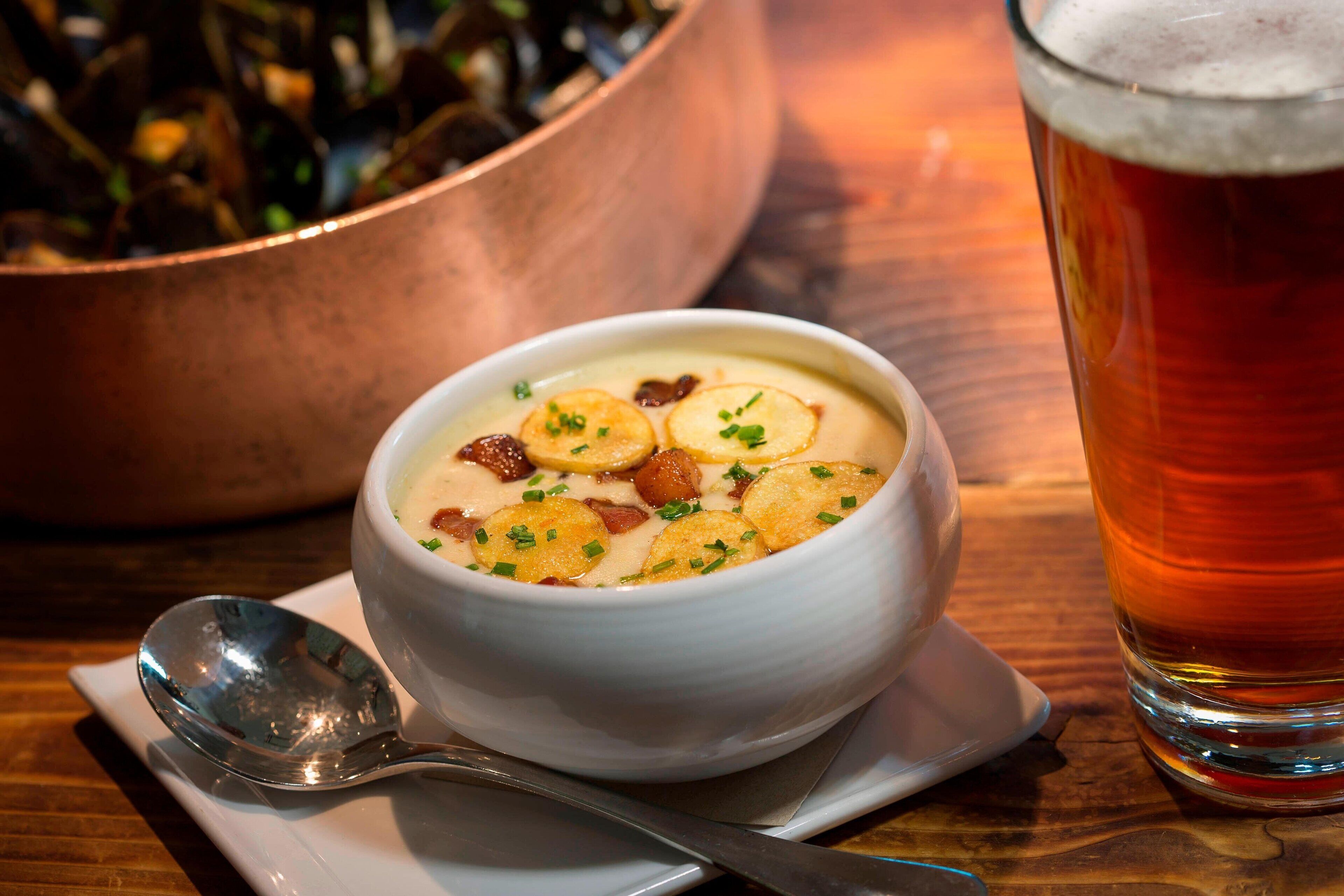 Un bol de soupe avec des croûtons et un verre de bière sur une table en bois.