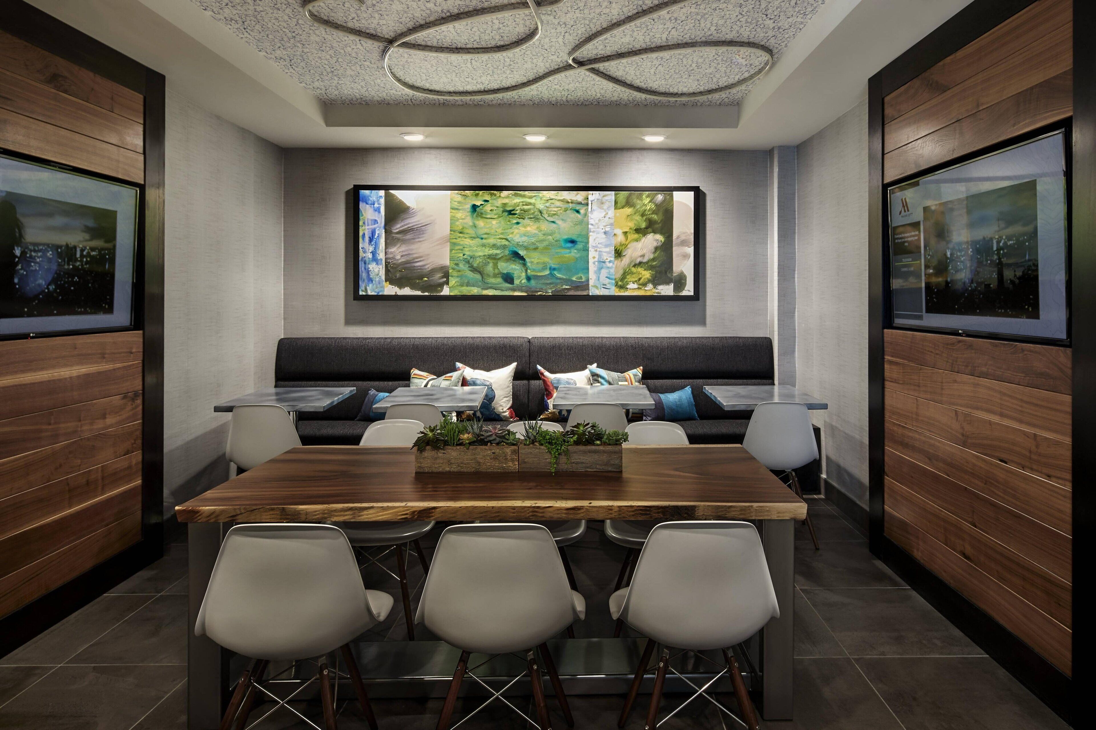 A modern meeting room with a long table, comfortable seating, and large abstract art on the wall.