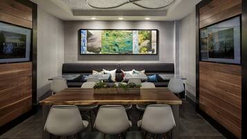 A modern meeting room with a long table, comfortable seating, and large abstract art on the wall.