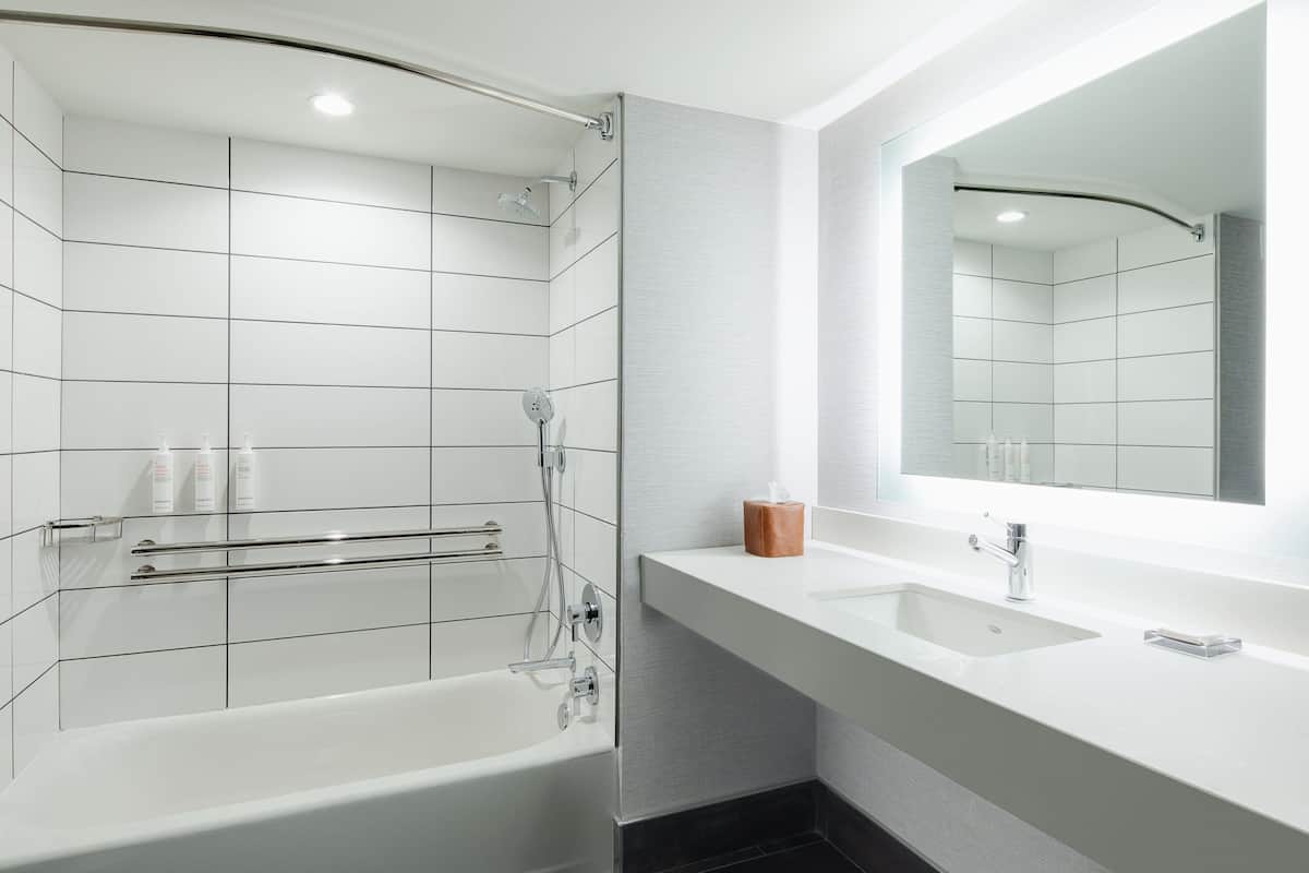 A modern bathroom with a bathtub, a vanity with a sink, and a large mirror.
