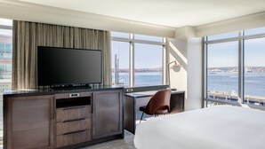 A modern hotel room with a large bed, a desk with a computer, a TV, and a view of a bridge and water. - Seattle Marriott Waterfront (Seattle)