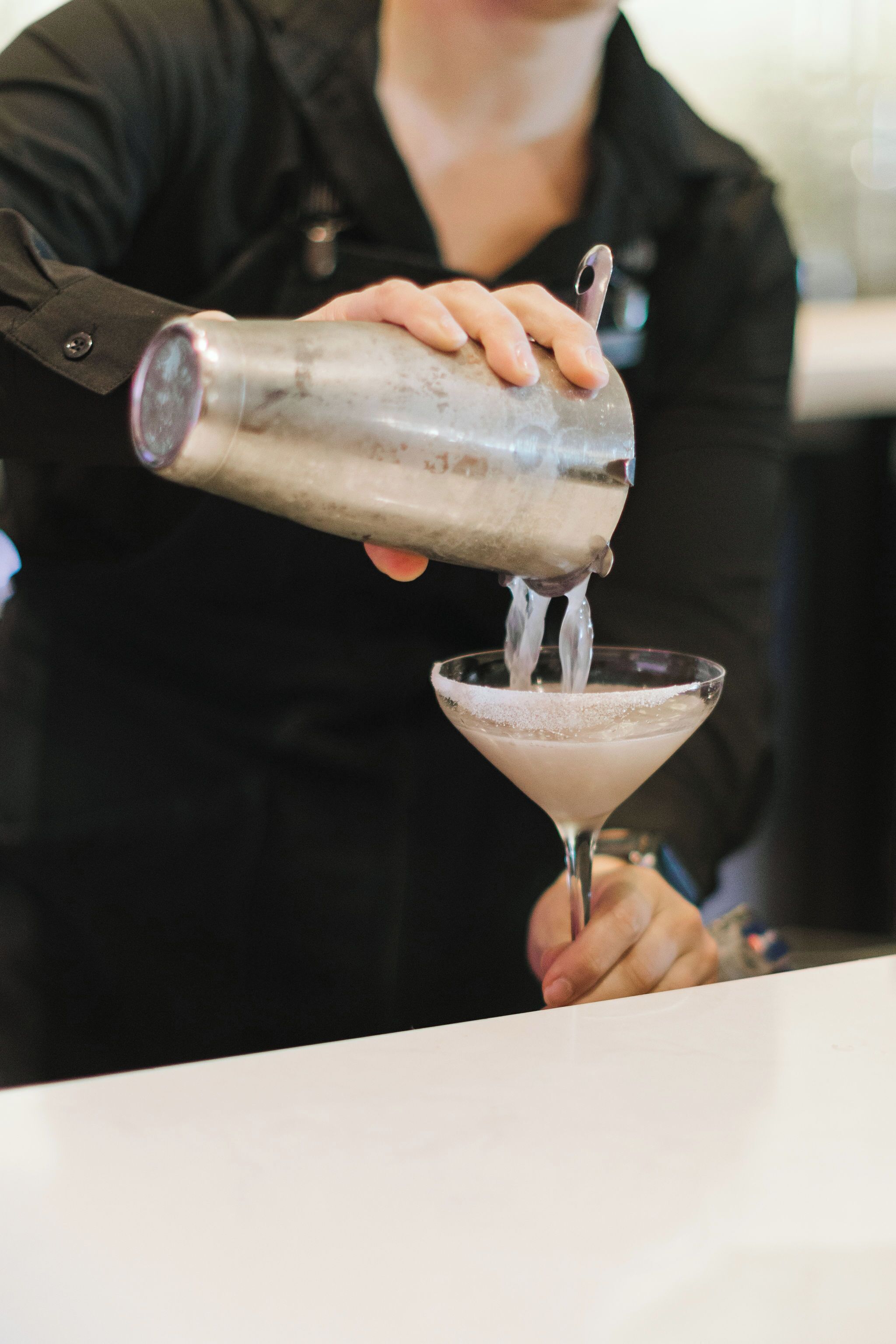 Un barista versa un drink in un bicchiere da martini.