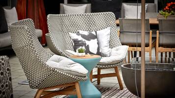 Un fauteuil de jardin en osier avec un coussin, une petite table et un foyer.