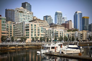 A marina with a white boat docked, surrounded by high-rise buildings and a clear sky.