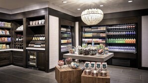 A well-organized retail space with shelves stocked with various products, a central display table, and a chandelier.