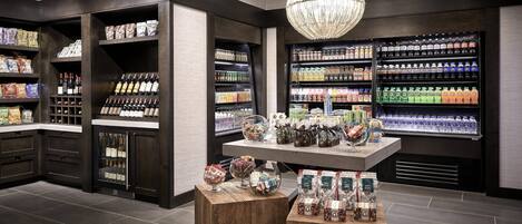 A well-organized retail space with shelves stocked with various products, a central display table, and a chandelier.