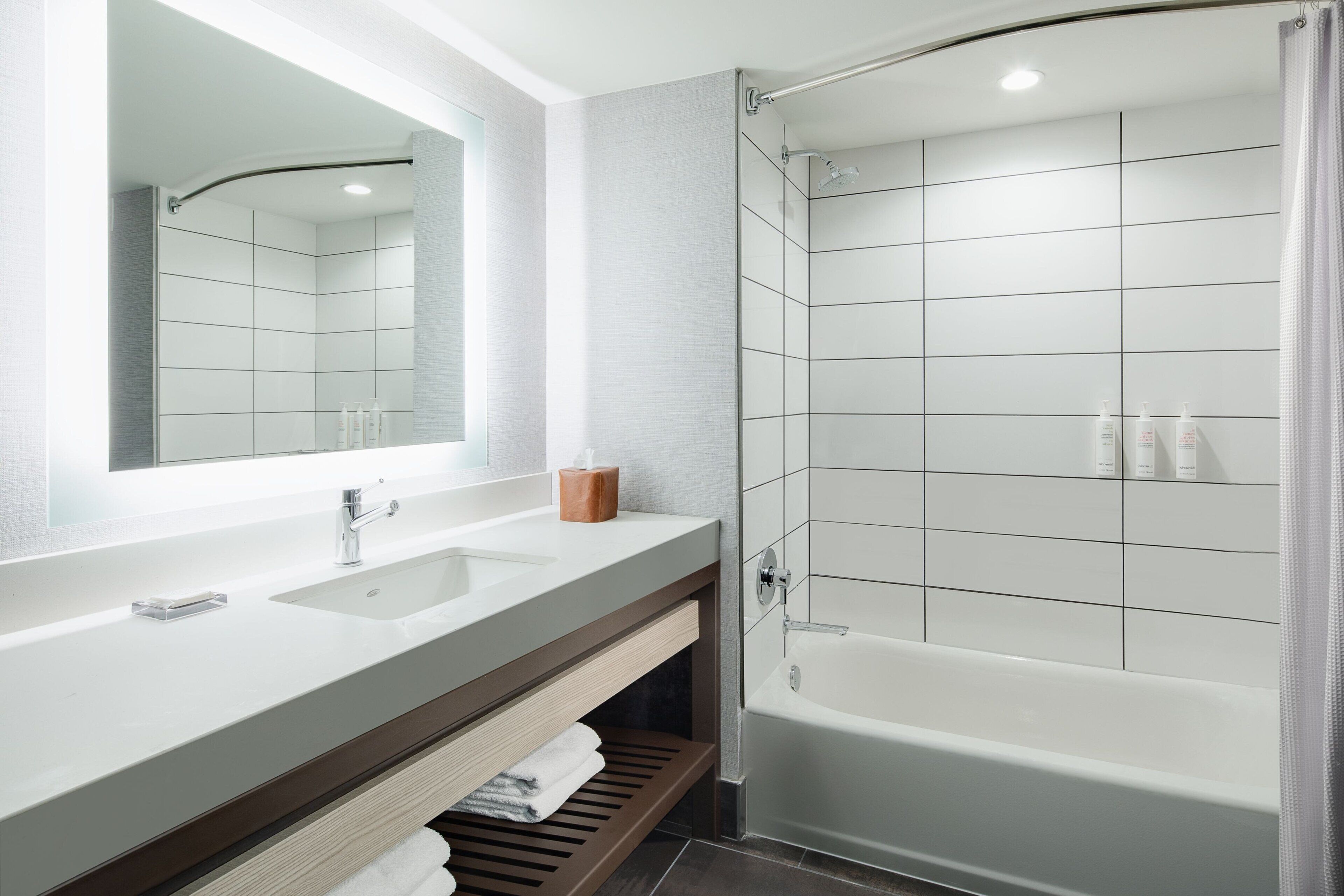 Un baño moderno con un espejo grande, dos lavamanos, ducha y bañera.