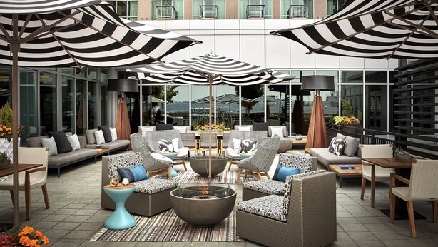 A modern outdoor lounge area with multiple seating options, including sofas and chairs, arranged around a central fire pit.