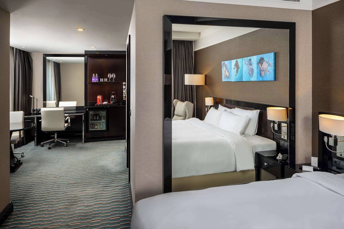 A hotel room with a bed, bedside tables, a desk, and a chair.