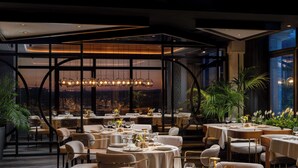 A restaurant with round tables, chairs, and a view of the cityscape through large windows. - Radisson Blu Leogrand Hotel (Chisinau)