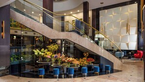 A modern lobby with a curved staircase, glass railings, and a central floral arrangement. - Radisson Blu Leogrand Hotel (Chisinau)
