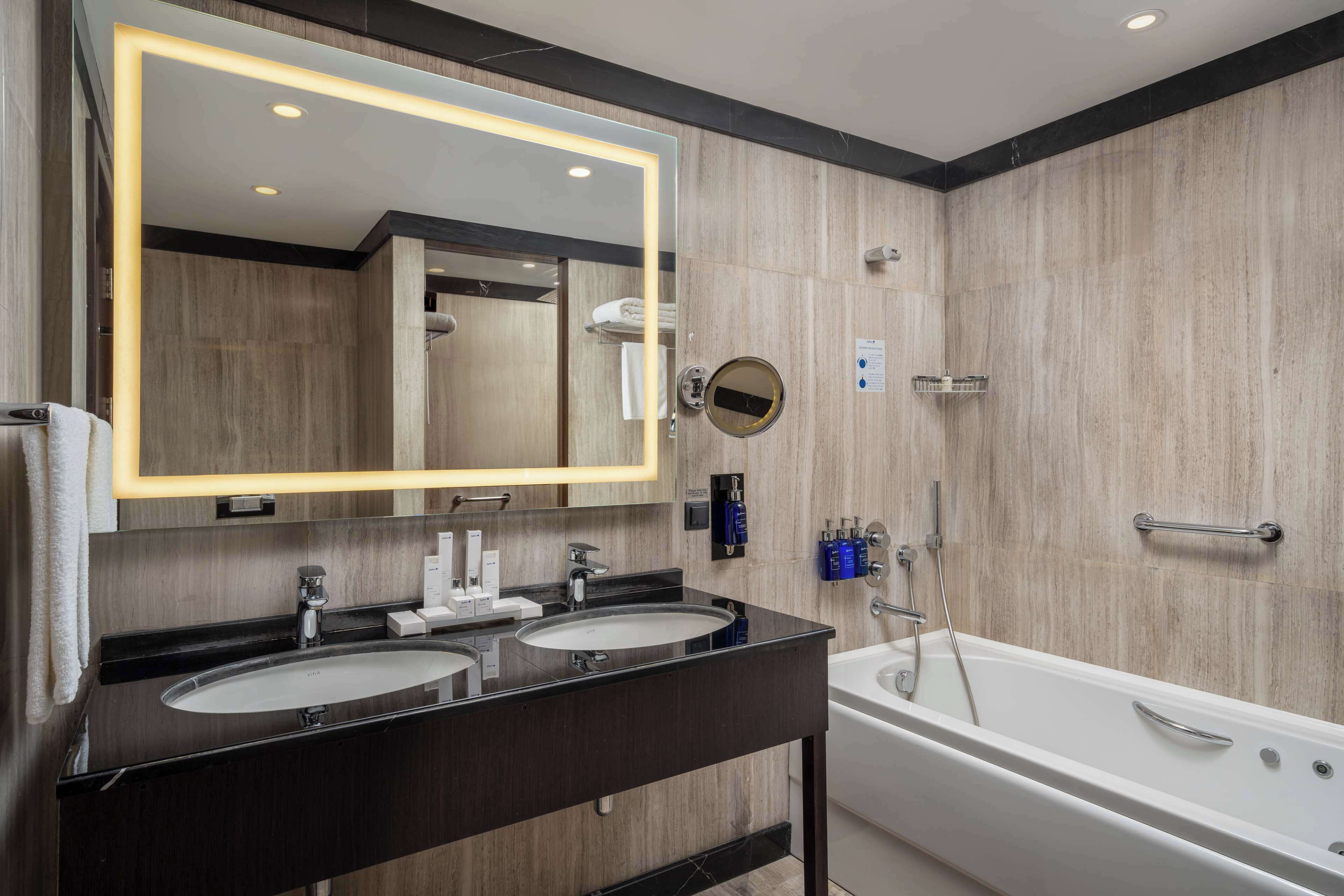 Un baño moderno con dos lavamanos, un espejo grande y una bañera.