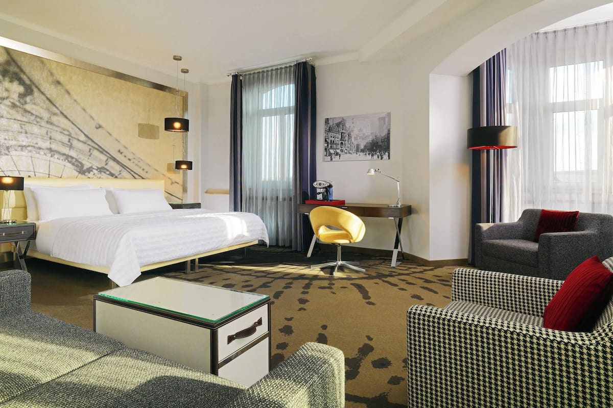 Une chambre d’hôtel avec un grand lit, un bureau, une chaise et un canapé.