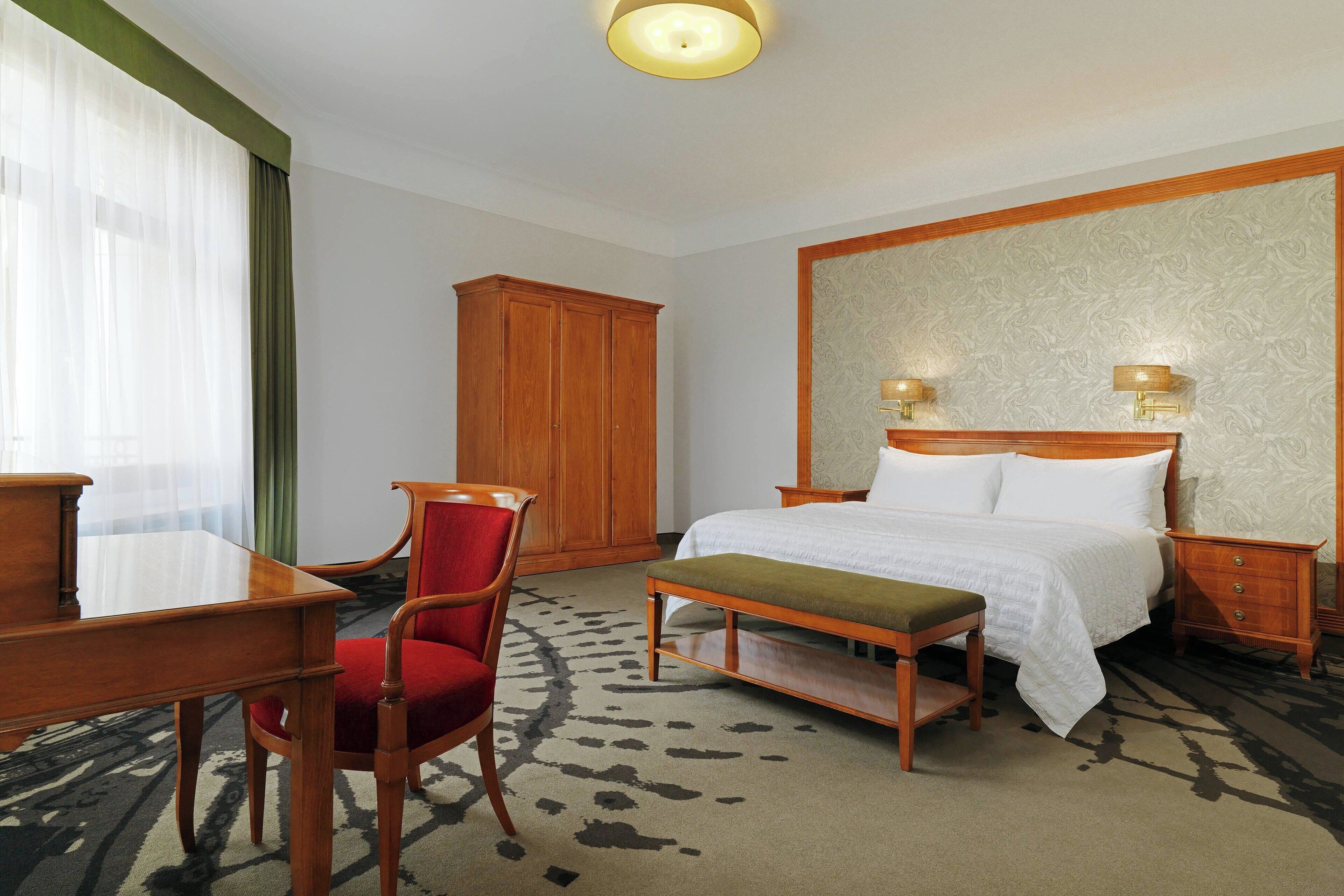 Een hotelkamer met een bed, een bureau, een stoel, een nachtkastje en een kledingkast.