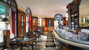 Zona de bar con mobiliario de madera, una encimera de mármol y una variedad de botellas y copas.