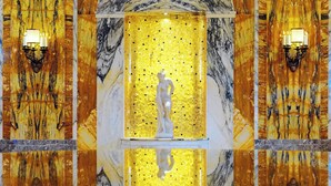 Pared de mármol con un panel de mosaico y una estatua.