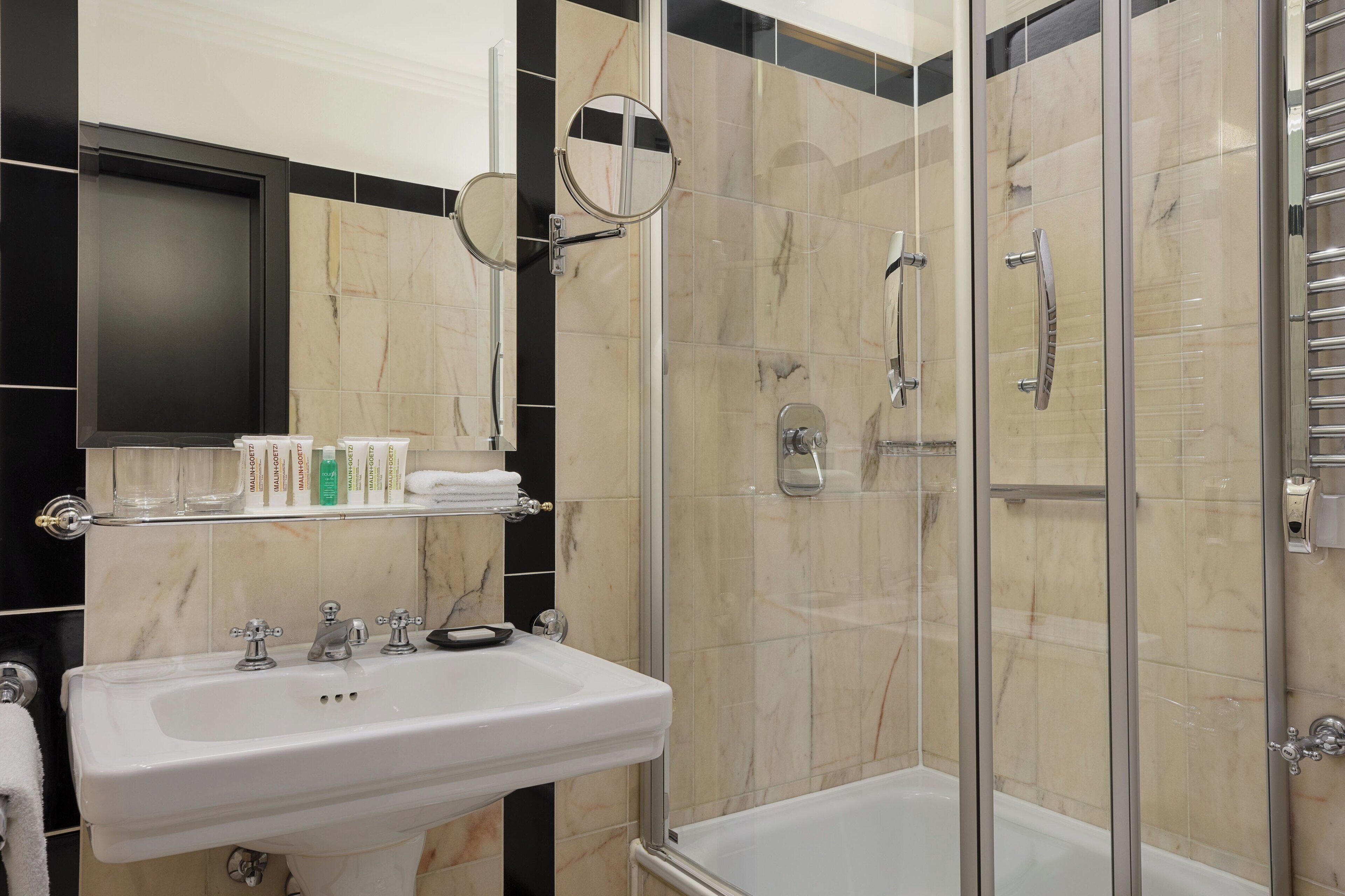 A bathroom with a white sink, a glass-enclosed shower, and a mirror above the sink.