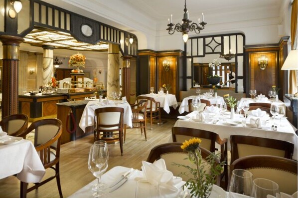 Un restaurante con varias mesas dispuestas para comer, sillas de madera y un candelabro.