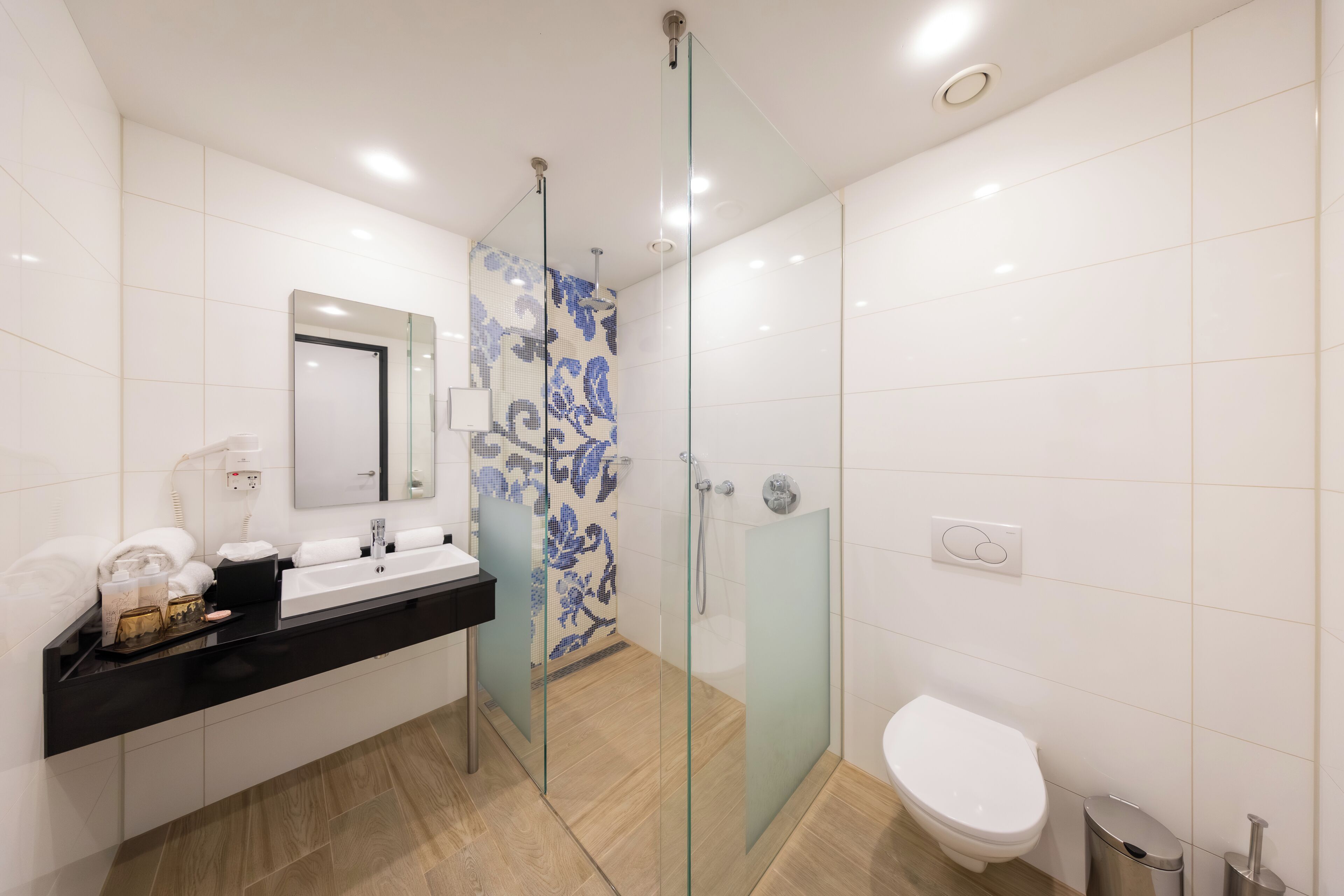 Une salle de bain moderne avec une douche à parois de verre, un lavabo blanc et des toilettes.