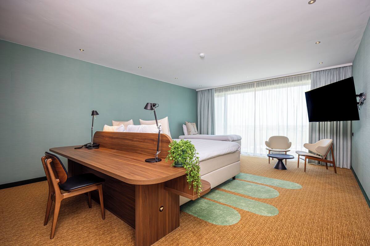 Camera d'albergo con una scrivania in legno, un letto, una TV e due sedie.