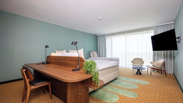 Una habitación de hotel con un escritorio de madera, una cama, un televisor y dos sillas.