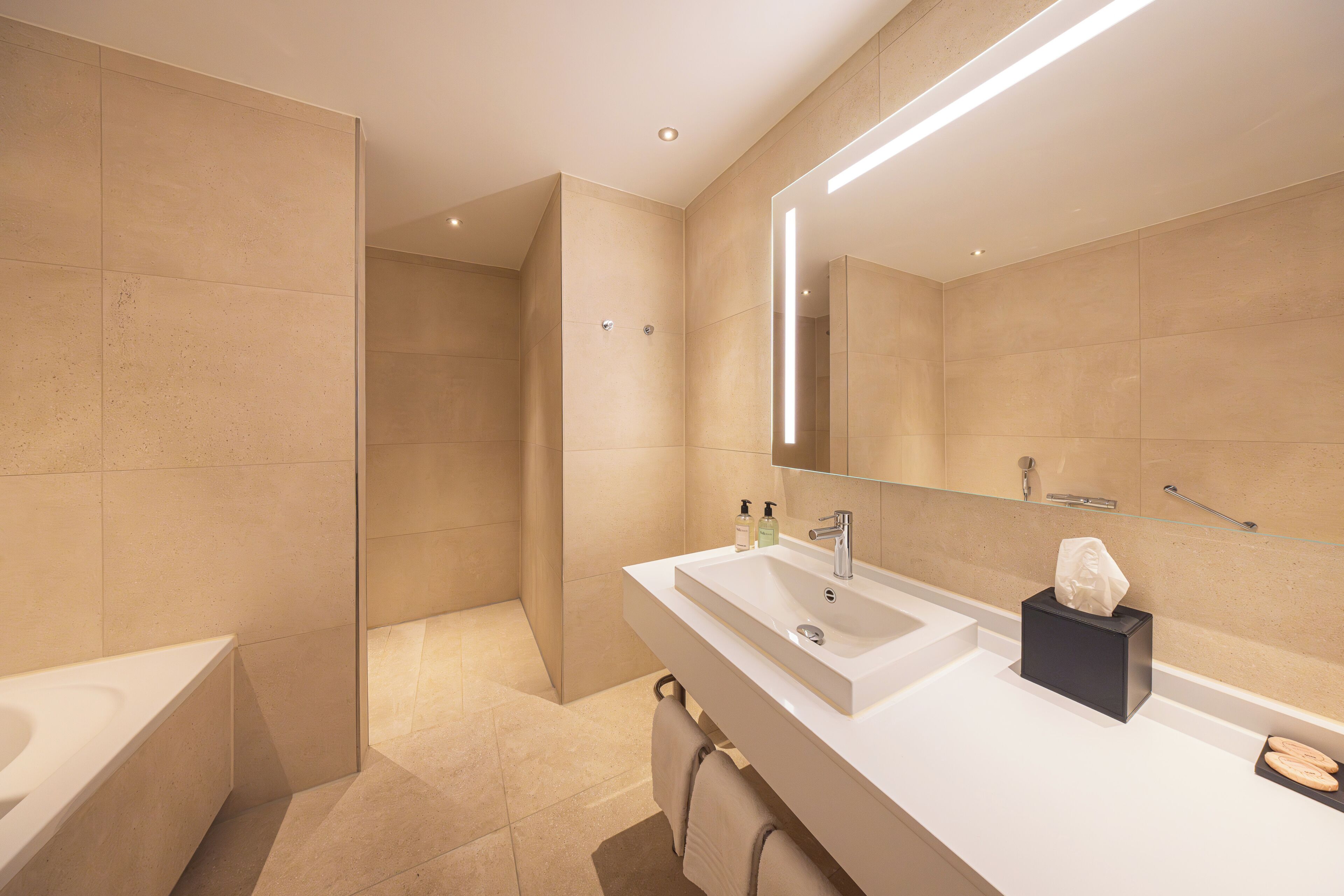 Un baño moderno con bañera, lavabo con espejo y toallero.