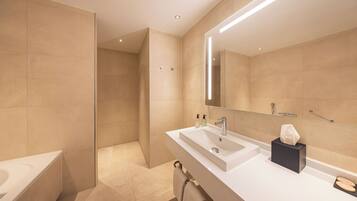 Un baño moderno con bañera, lavabo con espejo y toallero.