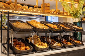 A bakery display with various breads and pastries in wicker baskets.