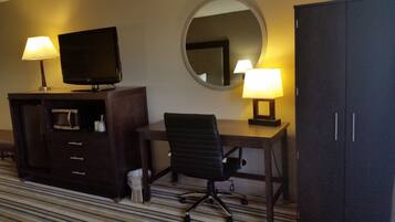 Una habitación de hotel con escritorio, silla, televisor y dos lámparas.